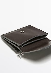 Portafoglio in pelle marrone con chiusura a scatto, caratterizzato da due scomparti e un piccolo anello metallico, con una texture liscia e un design pulito.