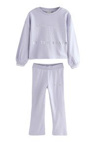 Lila tvådelad uppsättning med en kortärmad topp i cropped-stil med silvertext och matchande byxor med en figursydd design och logodetaljer.