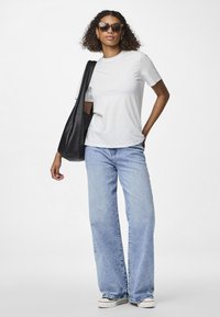 Hvit t-skjorte med korte ermer kombinert med lyseblå løstsittende jeans og svarte joggesko. Tilbehør med store solbriller og en svart veske.
