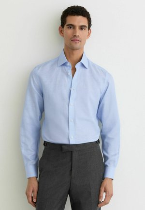 Cămașă deschisă la culoare, albastru deschis, cu design simplu și guler cu rever. Are mâneci lungi și textură netedă, asortată cu pantaloni gri închis.