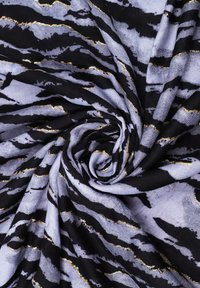 Tessuto elasticizzato con un motivo a strisce di tigre nero e lavanda, con accenti dorati metallici, arrotolato a forma di spirale. Texture liscia.