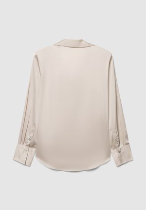 Camicia beige di seta a maniche lunghe con colletto classico, polsini con bottoni e una texture liscia. Una sottile lucentezza evidenzia la qualità del tessuto.