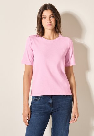 Light pink short-sleeved T-shirt with a round neckline. Soft texture and relaxed fit, paired with dark blue jeans in a straight cut.