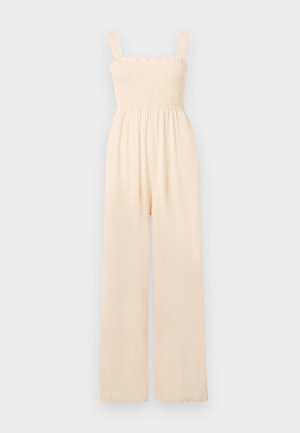 Combinaison beige pâle avec un corps smocké et de fines bretelles réglables ; design à jambes larges ; tissu doux et léger.