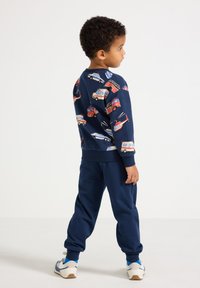 Mørkeblå outfit med en sweatshirt med farverigt bilprint og matchende joggingbukser, lavet af blødt materiale med en afslappet pasform.