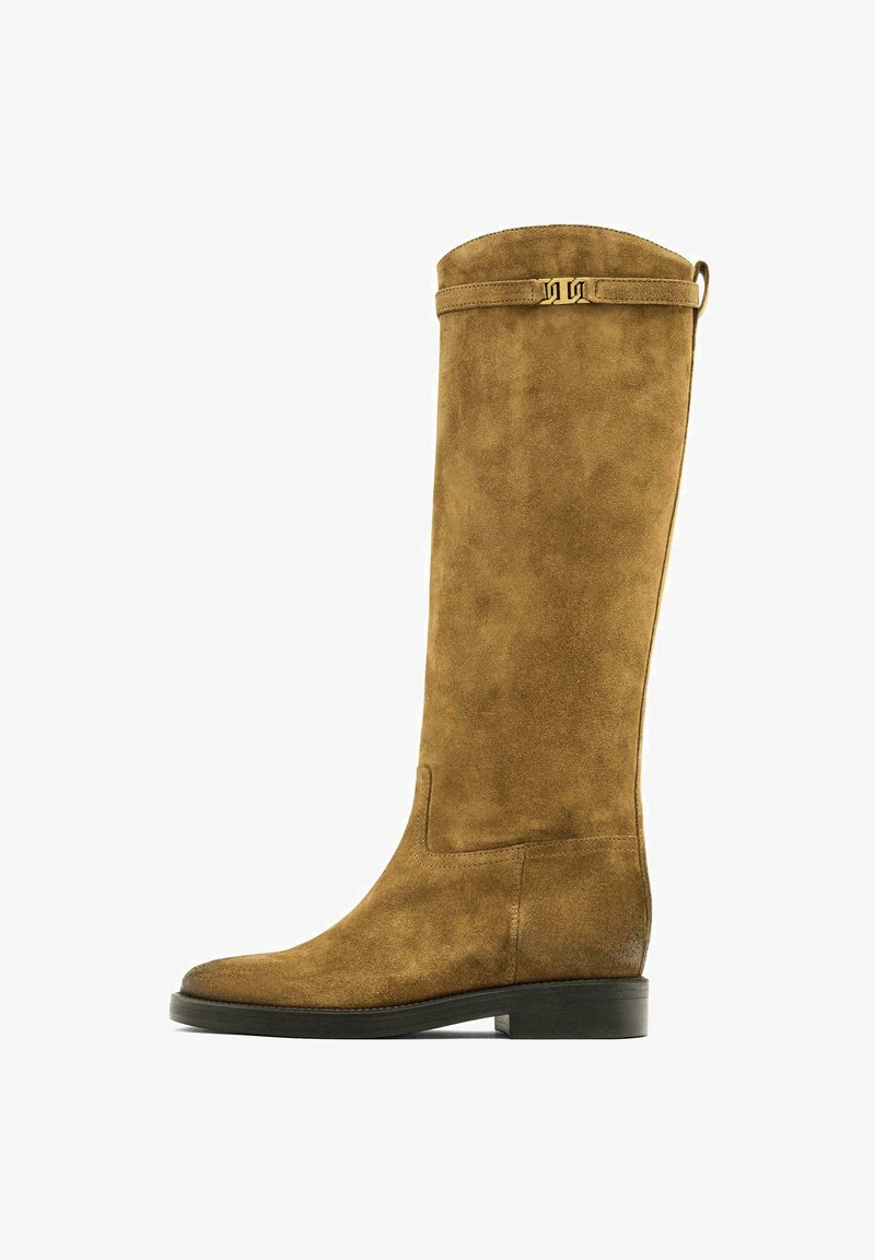 Sznurowane brązowe zamszowe botki do kolan z gładką teksturą, zaokrąglonym noskiem i płaskim obcasem. Posiadają złotą ozdobną taśmę u góry.