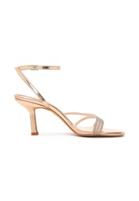 Sandalia de tiras en oro rosa con tacón de altura media, punta cuadrada y delgada correa al tobillo con cierre de hebilla, mostrada sobre fondo blanco.