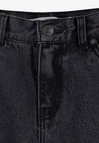 Jeans en denim noir présentant une texture lisse, une coupe droite classique, des coutures visibles et une fermeture à bouton en métal à la taille.