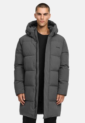 Grå pufferjakke med hette, glidelåslukking og store quilted seksjoner. På siden er det en logo detalj langs glidelåsen. Materialet ser mykt ut.