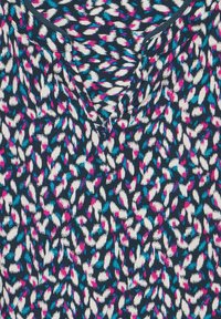 Tessuto scuro con uno sfondo navy che presenta un motivo colorato di piccole foglie astratte in bianco, rosa e turchese. Design a V.