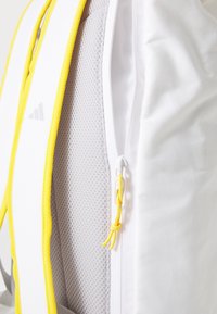 Backpack featuring a white fabric exterior, bright yellow accents, a zipper closure, and a textured gray mesh side panel.