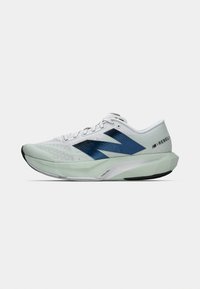 White athletic shoe with navy blue accents, mesh upper, rounded toe, and thick green sole. Features branding on the heel and side panels.