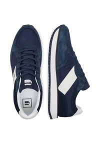 Tumši zili sporta apavi, kuros apvienoti zamšāda un gludu materiālu elementi, ar baltām detaļām un teksturētu gumijas zoli. Klasisks auklu aiztaisīšanas dizains.