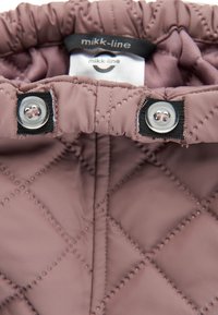 Wytłaczany, miękki materiał w odcieniu mauve o gładkiej teksturze. Posiada czarne zapięcia na zatrzaski oraz metkę z logo wewnątrz obszaru kołnierza.