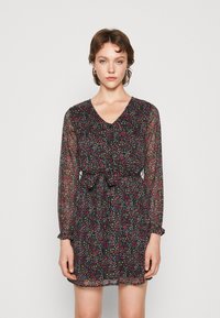 Vestido preto com estampado floral, mangas longas transparentes, decote em V, cintura ajustada e detalhes de babados nos punhos. Apresenta um padrão de flores coloridas.