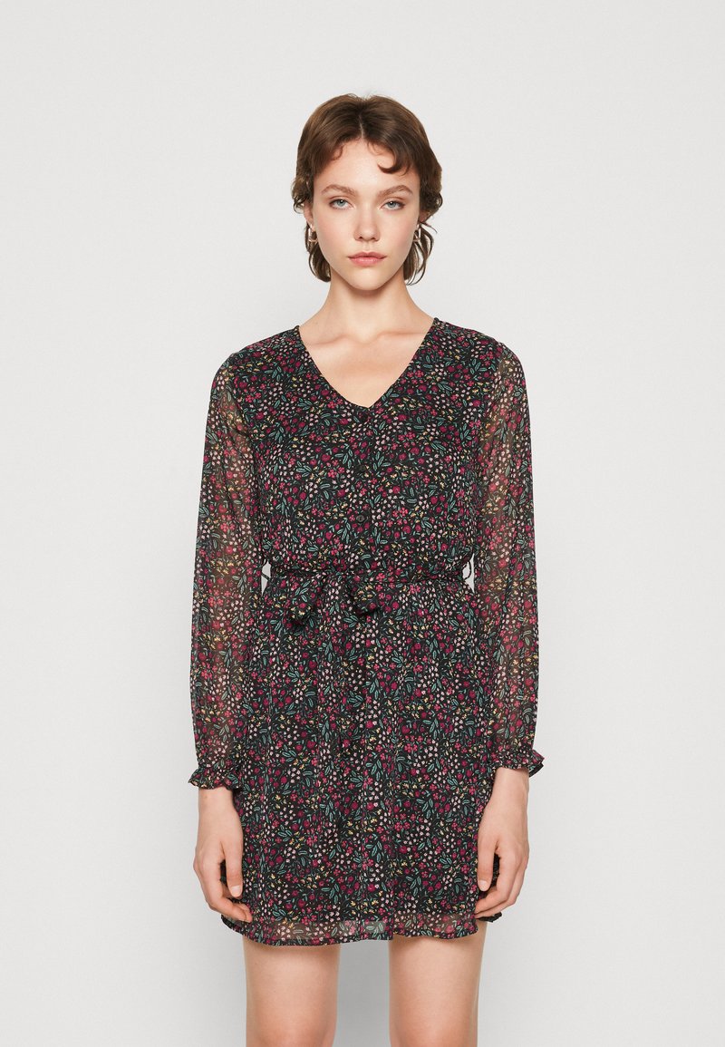 Vestido preto com estampado floral, mangas longas transparentes, decote em V, cintura ajustada e detalhes de babados nos punhos. Apresenta um padrão de flores coloridas.