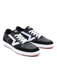 Svart og hvite sneakers med overdel i lær og semsket skinn, perforert tå, hvite snøringer og såle i gummi. VANS-logo på tungen.