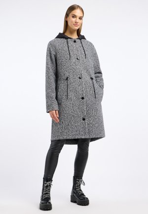 Grijze wollen blend jas met een zwarte capuchon, knoopsluiting, twee voorzakken en een middenlange snit, gecombineerd met zwarte nepleer leggings en laarzen.