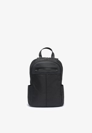 Compact black backpack with top handle, front zip pocket, side pockets, and MOMODESIGN logo on the upper front panel.