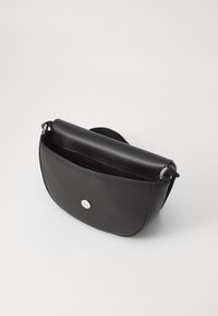 Borsa a tracolla in pelle nera con forma arrotondata, dotata di chiusura a scatto in argento e un interno morbido. Include una tracolla regolabile.