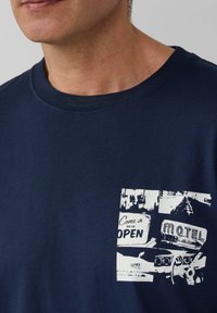 Navyblauw katoenen T-shirt met een ronde halslijn, voorzien van een witte grafische print van vintage borden op de linkerkant van de borstzak.