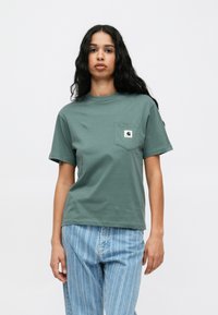 Roheline lühikeste varrukatega T-särk, rinnatasku, valmistatud puuvillast, logo sildiga. Kombineeritud helesiniste triibuliste teksadega.