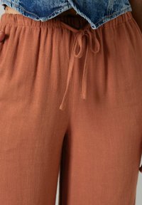 Rdzaw kolor lnu spodnie z elastycznym paskiem, charakteryzujące się miękkim, teksturowanym materiałem i luźnym krojem, odpowiednie do codziennego noszenia.