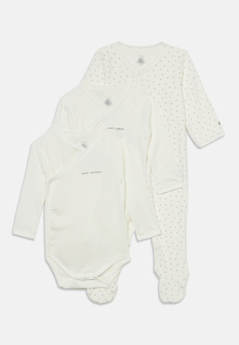 Trois vêtements blancs pour bébé à manches longues, comprenant une grenouillère pied avec de petits motifs foncés et deux bodies cache-cœur avec texte en français.