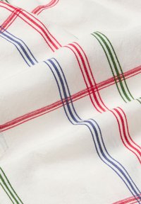 Katoenen stof met een witte basis en rood, blauw en groen geruite strepen. Gladde textuur met fijne stiksels en kruisingen.