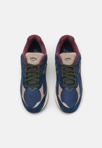 Blue sneakers with mesh and suede upper. Features green laces, maroon accents on the collar, and a reflective silver "N" logo.