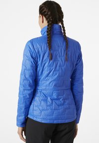 Modrá zateplená bunda s prošívaným vzorem, vysokým límcem a dlouhými rukávy. Hladká struktura a přiléhavý silueta zdůrazňují design.