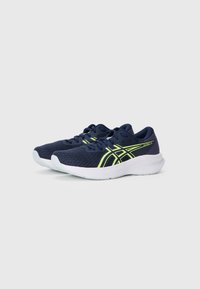 Baskets de course navy avec une tige en mesh texturé, présentant des accents jaunes fluorescents et une semelle blanche rembourrée.