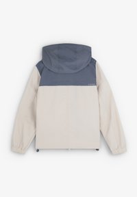 Veste légère à capuche présentant un corps crème et un panneau supérieur gris foncé. Les poignets élastiques et l'ourlet à cordon permettent un ajustement réglable.