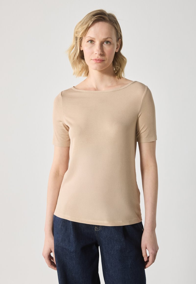 T-shirt beige ajusté à manches courtes, texture côtelée, décolleté large et finition lisse, associé à un pantalon en denim foncé.