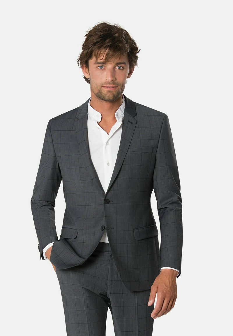 Grijze plaid colbert met notch-lapels en twee knopen, gecombineerd met een witte blouse, gepresenteerd op een mannelijk model.