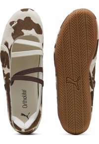 Bailarinas con estampado de vaca en marrón y blanco, con tiras cruzadas, material suave, plantilla Ortholite acolchada y suela de goma texturizada.