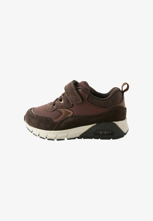 Brązowy sportowy sneaker z detalami z siateczki i zamszu, paskiem na rzep, wyściełanym kołnierzem oraz grubą białą i czarną podeszwą z oknem amortyzacji powietrznej.