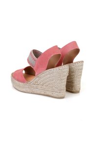 Sandales compensées en suède rose avec un talon en jute tissé et une bride de cheville élastique, dotées d'un design découpé et de motifs sur la bride.