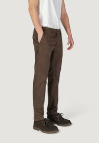 Pantaloni in cotone marrone con una vestibilità dritta, dotati di tasche laterali e una texture liscia, abbinati a scarpe stringate marrone scuro.