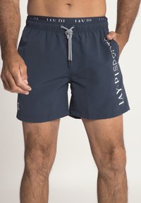 Námořnické modré plavky vyrobené z lehkého materiálu, s elastickým pasem a šňůrkou, boční kapsou a bílým potiskem loga.