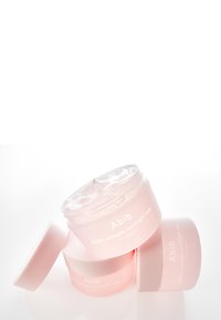 Barattoli di plastica rosa contenenti una maschera notturna gel-like impilati inclinati, con coperchio trasparente ed etichetta con testo bianco.