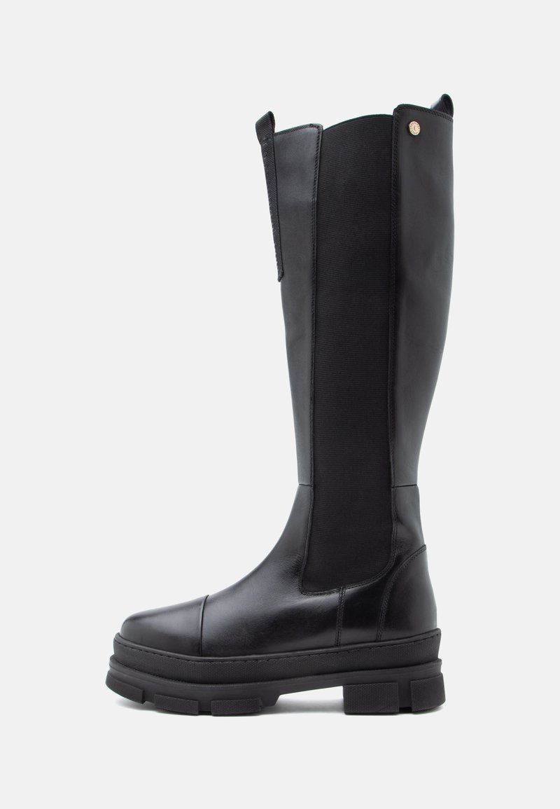 Botas negras de caña alta que cuentan con una parte superior de cuero liso, paneles laterales elásticos, suela de goma plana con un grosor pronunciado y diseño de puntera redonda.