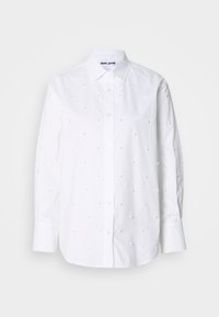Camicia bianca di cotone con maniche lunghe, colletto alla coreana, decorata con piccoli dettagli simili a perle, distribuiti uniformemente.