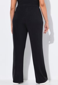 Zwarte loungebroek met een relaxte pasvorm, elastische tailleband en een gladde textuur; heeft een rechte pijp en minimale details.
