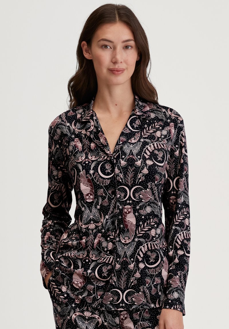 Zwart pyjamajack met lange mouwen, voorzien van een bloemen- en dierenontwerp in roze en wit, met een kraag en knopen aan de voorkant.