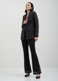 Black formal blazer with lace long sleeves, paired with black lace flared pants. The outfit features tailored design and textured patterns.