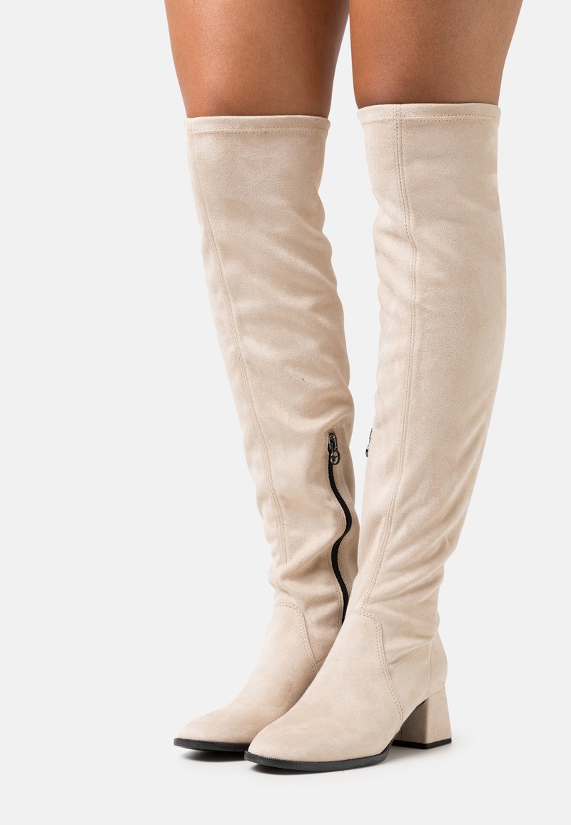 Beige Wildleder-Stiefel über das Knie mit Blockabsatz, ausgestattet mit einem seitlichen Reißverschluss und einer glatten, strukturierten Oberflächenbeschichtung.