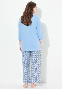 Lichtblauw langemouw top gecombineerd met losse, patroonpyjamabroek met een golvenontwerp in blauw en wit. Zachte katoenmateriaal.