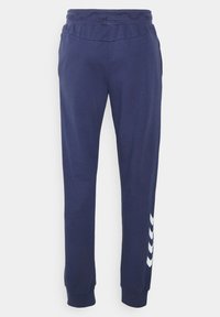 Helle marineblaue Jogginghose aus weichem Stoff, mit einem elastischen Bund, schmal zulaufenden Beinen und einem weißen Chevron-Muster auf der linken Seite.