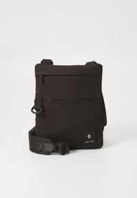 Compact black crossbody bag with adjustable strap, two horizontal zippered pockets, and a small brand logo patch on the front bottom right.